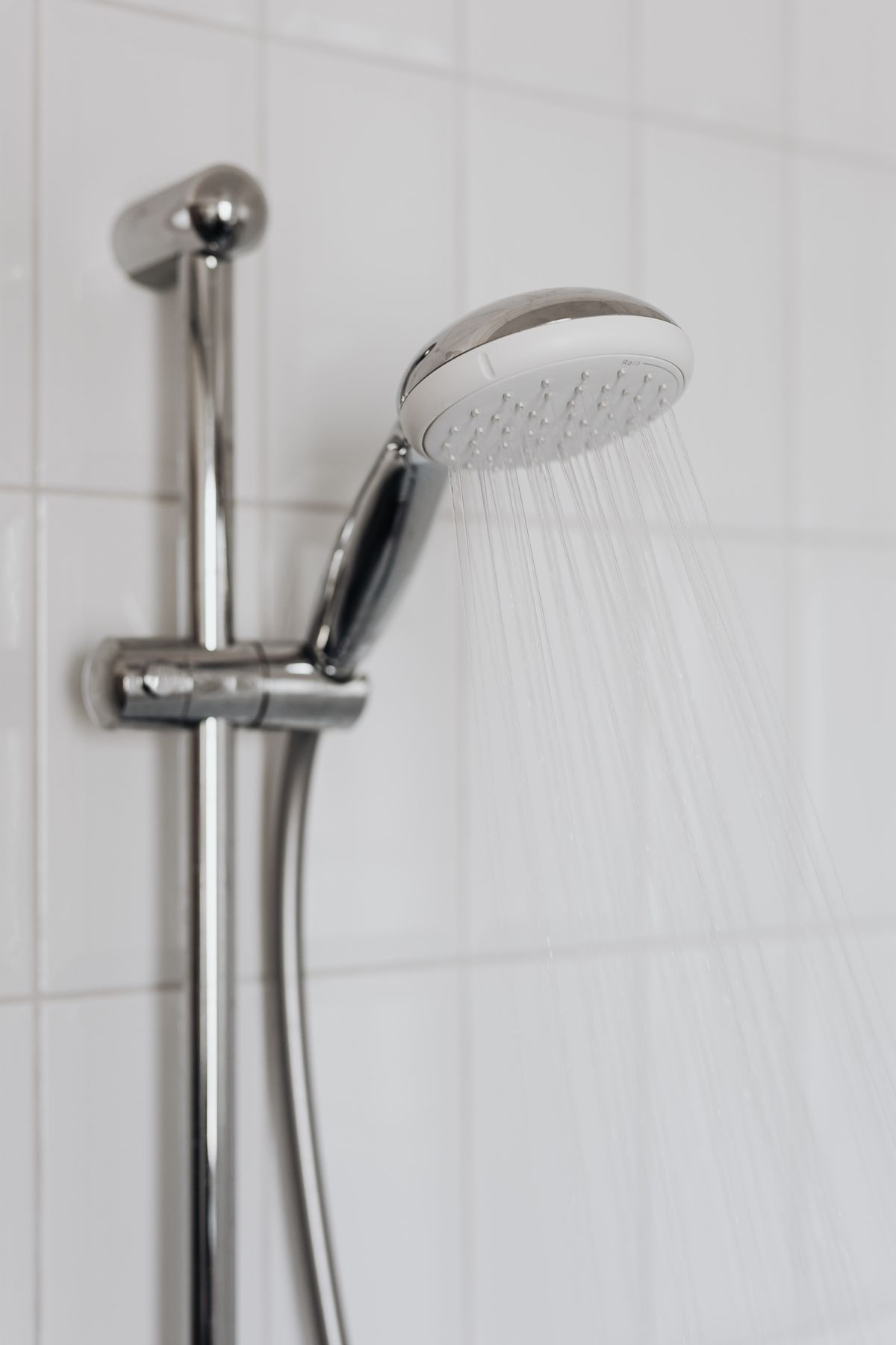 Emergency shower repairs A chrome shower head running in a tiled bathroom